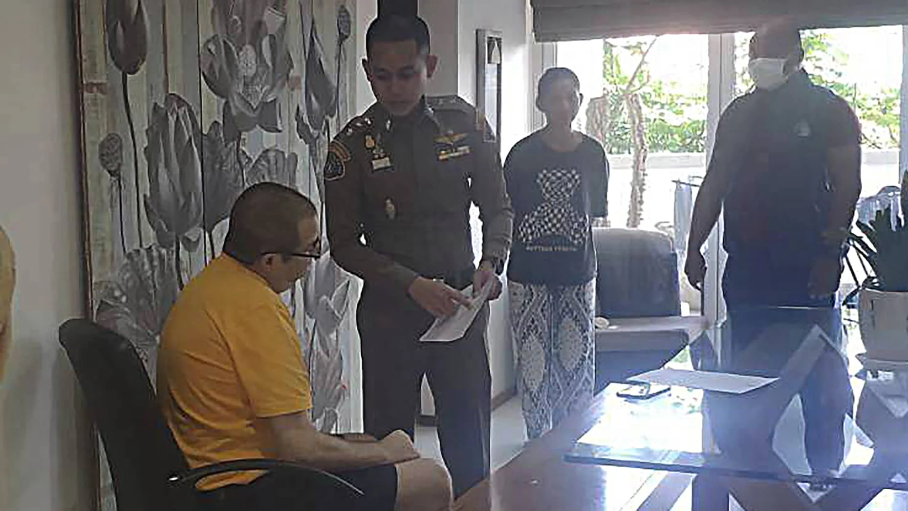 Peter Coker Jr., left, is issued search warrants from police at his villa on the southern resort island of Phuket, Thailand, Jan. 11, 2023.